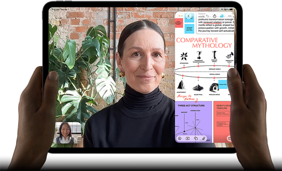 iPad Pro, front exterior, landscape orientation, space black colour, rounded corners, black display bezel, hands holding left and right sides, display showing a FaceTime conversation being live translated, and an educational app showing a presentation of Comparative Mythology with text, diagrams and handwritten notes