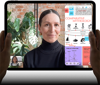 iPad Pro, front exterior, landscape orientation, space black colour, rounded corners, black display bezel, hands holding left and right sides, display showing a FaceTime conversation being live translated, and an educational app showing a presentation of Comparative Mythology with text, diagrams and handwritten notes