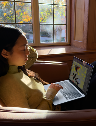A person sitting in a chair using their MacBook Air